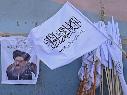 Un vendedor sostiene una bandera de los talibanes junto a una imagen del mulá Baradar, en Kabul. AAMIR QURESHI / AFP