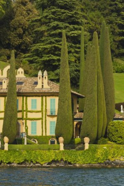 Vista desde el agua de una de las villas con cipreses a orillas del lago de Como.