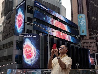 Un hombre fotografía las imágenes de una nebulosa obtenidas con el James Webb en Times Square, Nueva York.