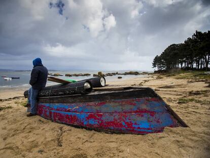 A poacher on the Arousa estuary leans on a boat used for the nightly raids. 