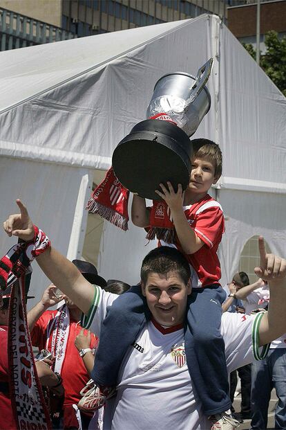 Padre e hijo sevillistas posan con una réplica de la Copa del Rey en el parque barcelonés de la Berrida.