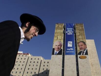 Dos ultraortodoxos pasan por delante de un cartel electoral de Benjamin Netanyahu y Avigdor Lieberman en Jerusal&eacute;n. 