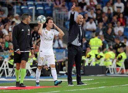 Álvaro Odriozola saca un balón mientras Zinedine Zidane gesticula.