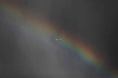 Un avión de carga de la compañía Cygnus Air sobrevuela el cielo atravesando un arco iris tras despegar del aeropuerto de Madrid, Adolfo Suárez Barajas.
