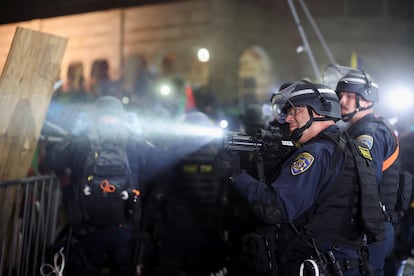 Un policía apunta hacia los manifestantes propalestinos durante la operación de desalojo del campus de UCLA. 