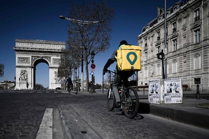 Un repartidor atraviesa unos Campos Elíseos casi vacíos, en París.