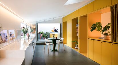 Libre de tabiques, un mueble de madera laminada de la marca Egger pintado en amarillo concentra armarios, zona de trabajo, puertas y estanterías. Las sillas son de Ikea. Y la mesa, del Rastro.