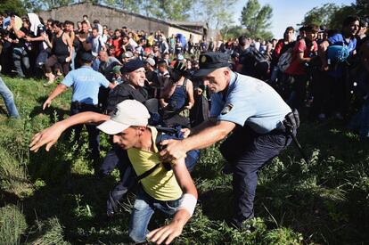 En Tovarnik, varios miles de refugiados esperaban durante horas en la estación de trenes para ser transportados de forma organizada hasta los centros de acogida en Zagreb y otras localidades croatas. En la imagen, un policía intenta impedir el paso a un refugiado en Tovarnik (Croacia).