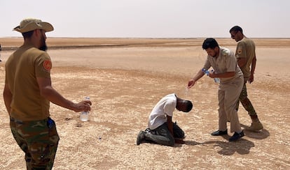 A Libyan border agent dribbles water on an African migrant at the Libyan-Tunisian border, on July 30, 2023.