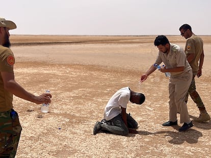 A Libyan border agent dribbles water on an African migrant at the Libyan-Tunisian border, on July 30, 2023.