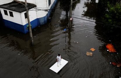 Un trabajador utiliza una tabla para moverse por las calles inundadas tras las fuertes lluvias que asolaron São Paulo (Brasil), el 7 de abril de 2017.