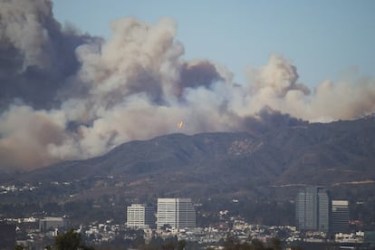 Un avión vuela para arrojar retardante de fuego sobre el área del incendio forestal.