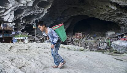 Un niño residente en la cueva de Zhongdong (China), transporta un cesto a la espalda en las afueras de la caverna. Los menores que viven aquí tienen muchas dificultades para ir a la escuela.