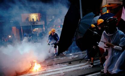 Manifestantes se protegen de gases lacrimógenos durante una protesta este domingo en Hong Kong.