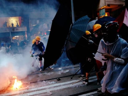 Manifestantes se protegen de gases lacrimógenos durante una protesta este domingo en Hong Kong.