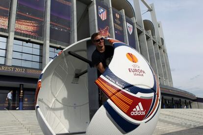 Un aficionado posa en el interior de un balón gigante en los exteriores del estadio.