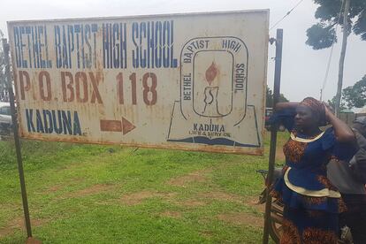 Familiares de los estudiantes secuestrados junto al cartel de la escuela baptista Bethel en Kaduna, en el noroeste de Nigeria, este lunes.