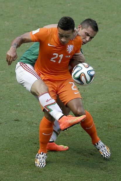 El jugador holandés Memphis Depay, pelea el balón con el mexicano Paul Aguilar.