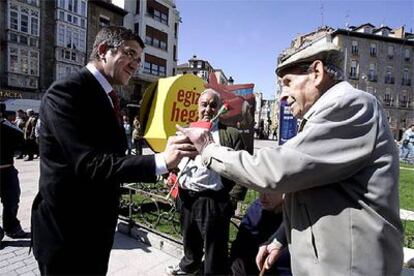 El líder del PSE-EE, Patxi López, entrega claveles en una plaza de Vitoria.