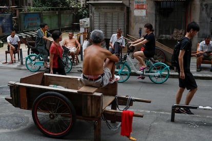 Los trabajadores descansan en carritos de mano mientras los jóvenes profesionales se deslizan en las coloridas bicicletas compartidas que abarrotan las ciudades de China. En la imagen, un hombre se sienta en su carro esperando clientes en una calle del mercado en el barrio tradicional de Yuexiu en Guanghzou.