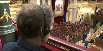 Un hombre utiliza unos cascos en el hemiciclo del Congreso de los Diputados.