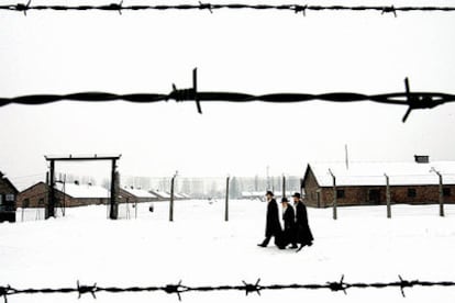 Tres judíos ortodoxos caminan por el recinto del antiguo campo de exterminio nazi de Auschwitz antes de la conmemoración.