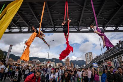 Personas realizan una danza aérea colgadas de telas bajo un puente peatonal, durante la marcha del Orgullo LGBT en Bogotá (Colombia).
