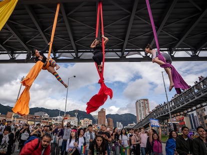 Personas realizan una danza aérea colgadas de telas bajo un puente peatonal, durante la marcha del Orgullo LGBT en Bogotá (Colombia).
