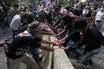 Manifestantes opositores intentan romper una barricada en Bangkok.