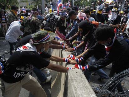 Manifestantes opositores intentan romper una barricada en Bangkok.