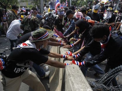 Manifestantes opositores intentan romper una barricada en Bangkok.