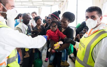 Agentes de la Guardia Civil hacen gestos a una niña junto a su madre en el interior del buque 'Aquarius' a su llegada a Valencia.