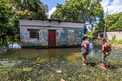 Las personas, con el agua por las rodillas, intentan recuperar sus pertenencias en pequeñas casas, algunas construidas con láminas de metal. Una mujer y su hijo tratan de llegar a su vivienda en San Félix, en el Estado de Bolívar.