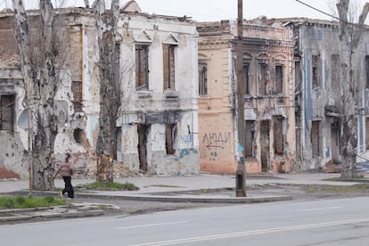 Una niña pasea junto a unos edificios destruidos en el centro de Mariupol
