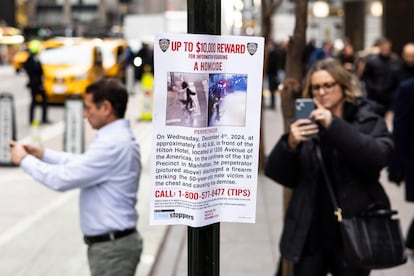 Varias personas hacen fotos a los carteles de reclamo para buscar al asesino de Brian Thompson en Nueva York.