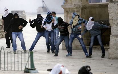 Un grupo de jóvenes palestinos lanzan piedras contra policías isralíes.