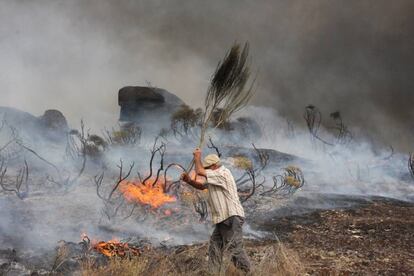 Un hombre trata de sofocar las llamas del incendio desatado la poblacin de Almeidinha, en el distrito de Guarda, cerca de la frontera con la provincia espa?ola de Salamanca, donde las llamas han llegado hasta el casco urbano.