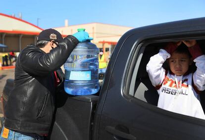 Un hombre coloca una garrafa de agua en su camioneta en Kyle, Texas, mientras su hijo espera. Más de 700 sistemas de suministros de agua se habían visto afectados.