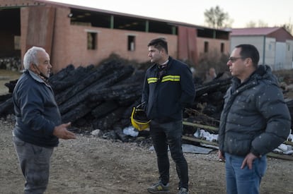 El ganadero Emilio Torrubia conversa con los dos bomberos para explicarles, delante de unas maderas que también se quemaron, que esos montes ahora arruinados contaban con unos bosques que él ayudó a plantar. La gente de la zona con sus tractores, añade, fue fundamental para impedir que los pueblos también fuesen arrasados por el fuego.