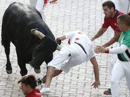 Un mozo es corneado por uno de los toros de la ganadería de Victoriano del Río durante del séptimo encierro de los Sanfermines, este jueves en Pamplona.