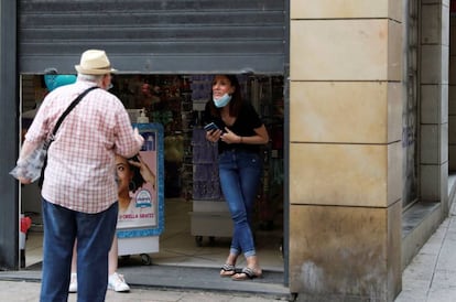 Una comerciant parla amb una persona amb la persiana mig abaixada a Lleida.