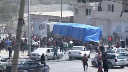 Un grupo de personas persigue un convoy de camiones de ayuda que entran en Gaza desde el cruce de Rafah, este martes.
