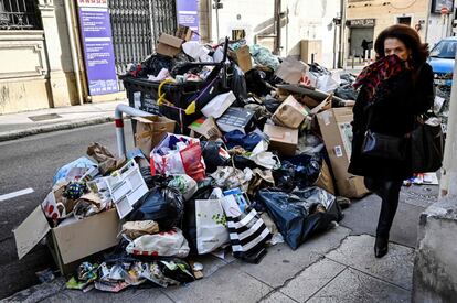 Una mujer camina al lado de gran cantidad de basura en una calle de Marsella (Francia). Los sindicatos FSU y CGT han llamado a bloquear dos centros de transferencia de residuos durante 10 días en protesta contra la reforma de las pensiones.