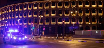 Un coche de policia circula junto a la plaza de toros de Valencia durante la medianoche de este sábado.