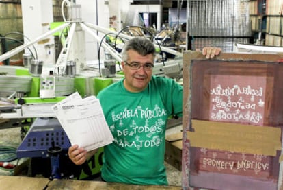 Isidro Álvarez posa con una de sus camisetas de la <i>marea verde </i>en su taller de Vallecas.