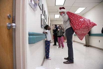 Barack Obama se viste de Papa Noel para repartir regalos de navidad entre los niños ingresados en el hospital infantil Children's National Medical Center, en Washington DC (EE UU). En la imagen, el expresidente conversa con un pequeño paciente.