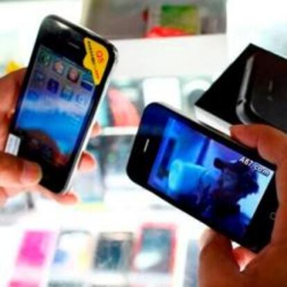 Un cliente sostiene iPhones falsos en una tienda de móviles en Shanghái