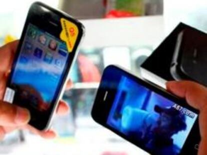 Un cliente sostiene iPhones falsos en una tienda de móviles en Shanghái