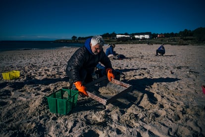 Varios voluntario intentan limpiar la arena de la playa de Area Maior.