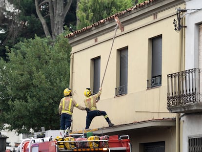 Dos bomberos retiran las tejas dañadas de una vivienda como consecuencia de la tormenta en La Bisbal.